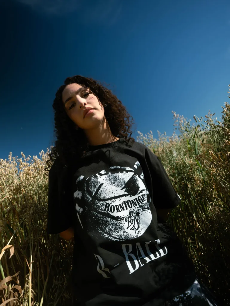 Femme en t-shirt R-BALL dans les hautes herbes, ciel bleu