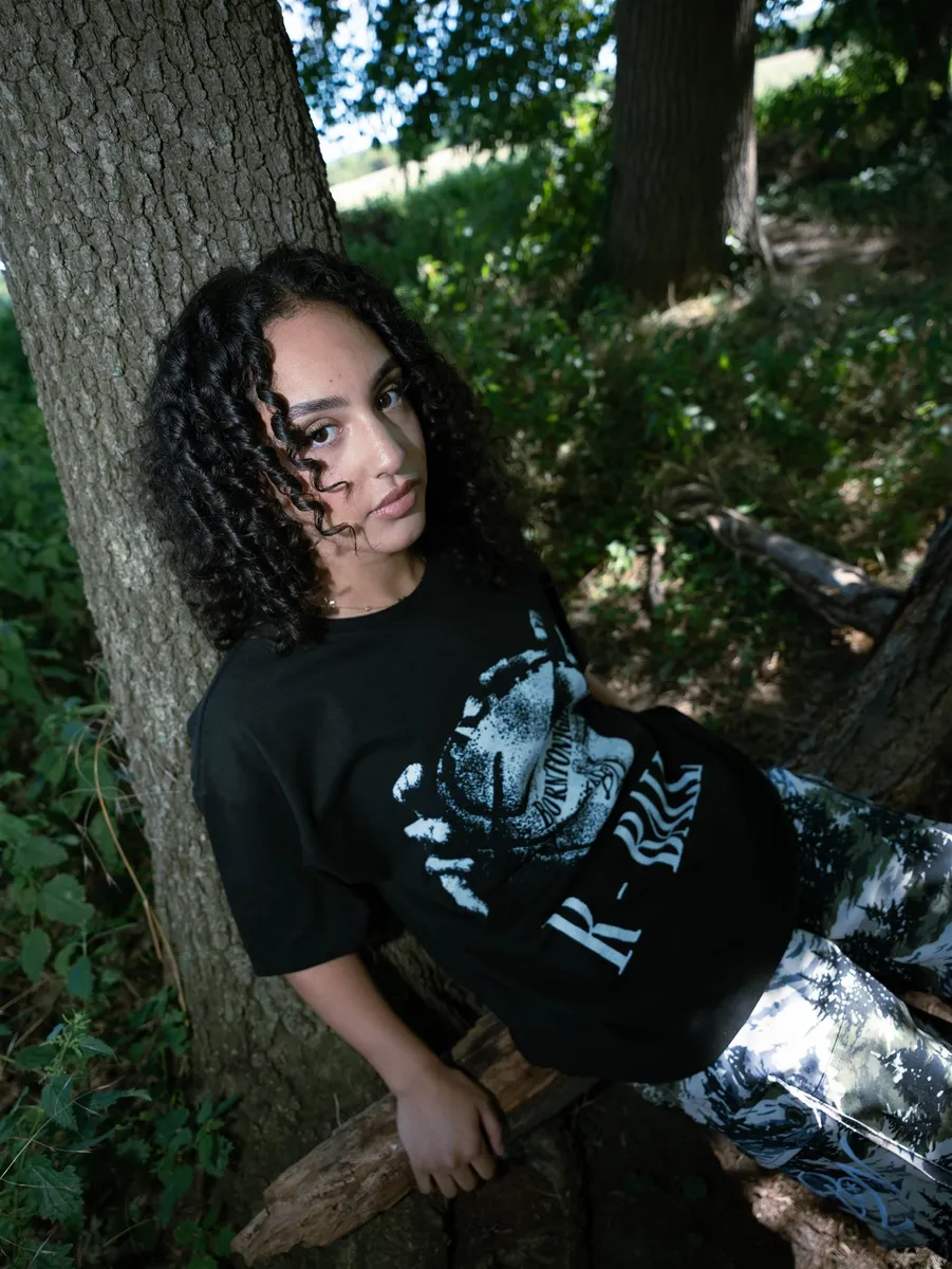 Femme adossée à un arbre en sous-bois, t-shirt B2N