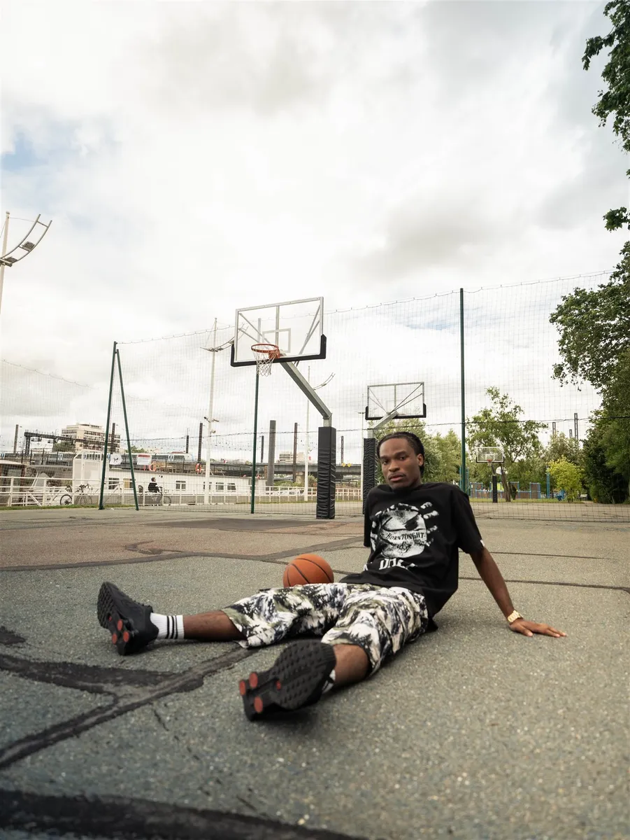Homme assis au sol sur un terrain de basket